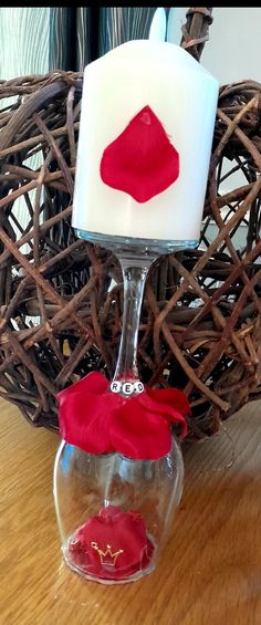 a candle with a red cloth on it sitting in a glass vase next to a basket