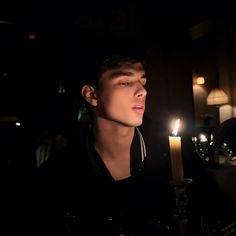 a young man sitting in front of a lit candle