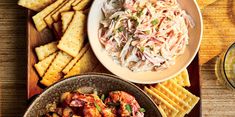 a bowl of coleslaw next to a plate of crackers on a table