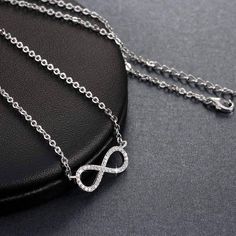 Centered between the two lengths of shiny silver tone chain, this miniature eternity symbol appears to float along the neck. Completely encrusted in micro CZ stones creating incredible shimmer. At only 2 cm this is truly subtle and graceful. This necklace is perfect for women, teens or young children. Length: 18 inch chain Stones: CZ Metal: Sterling Silver, 3 layers of platinum plating. Comes in a gift box. (Reg $45.99) Silver Infinity Clavicle Chain Jewelry, Silver Infinity Necklace In Dainty Style, Silver Infinity Dainty Necklace, Silver Dainty Infinity Necklace, Minimalist Silver Cubic Zirconia Chain Necklace, Dainty Silver Rhinestone Necklace For Gifts, Dainty Silver Infinity Necklace, Silver Infinity Jewelry, Silver Cubic Zirconia Necklace With Cable Chain