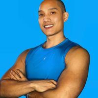 a man in a blue tank top posing for a photo with his arms crossed and smiling