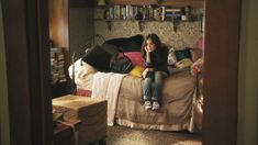 a woman sitting on top of a bed next to a book shelf filled with books