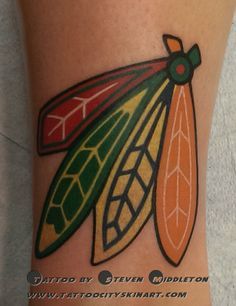 a tattoo design on the leg of a woman with an orange, green and red leaf