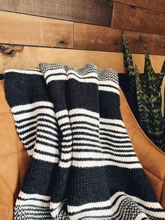 a black and white blanket sitting on top of a couch next to a potted plant