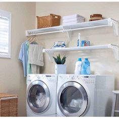 a washer and dryer sitting in a room next to a shelf with towels