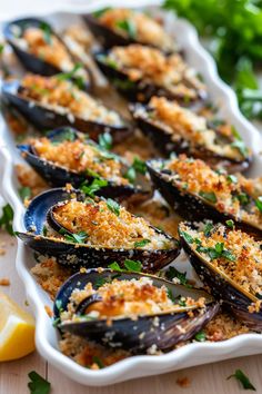 cooked mussels with parmesan cheese and herbs in a white dish on a wooden table