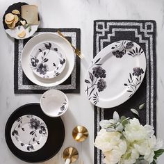 black and white plates with flowers on them sitting on top of a marble tablecloth