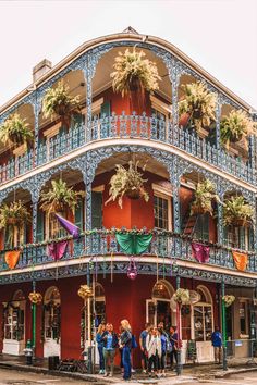 people standing in front of an ornate building with balconies and flowers on it