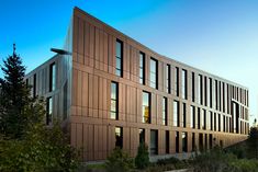 an office building with lots of windows on the front and side of it at dusk