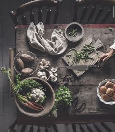 a wooden table topped with bowls filled with vegetables next to other dishes and utensils