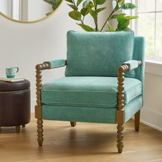 a blue chair sitting in front of a window next to a potted plant on top of a hard wood floor