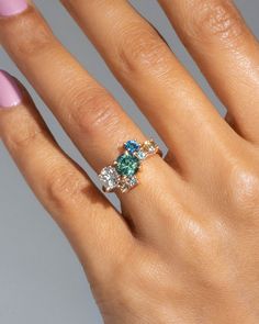 a woman's hand with a ring on it and three stones in the middle