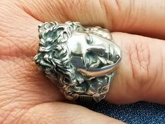 a man's silver ring with a lion head on the middle of his finger