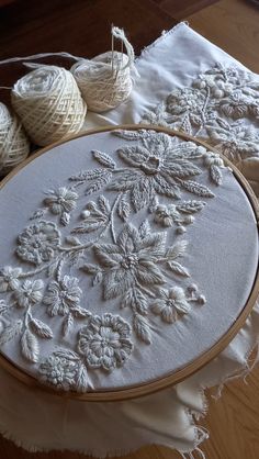 some balls of yarn sitting on top of a table next to an embroidered piece of cloth