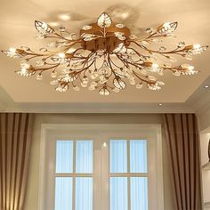 a living room filled with furniture and a chandelier hanging from the ceiling over a window