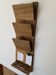 a wooden wall hanging organizer with notepads, pen and memo pad attached to it