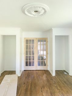 an empty room with white walls and wood floors, two doors are open on either side