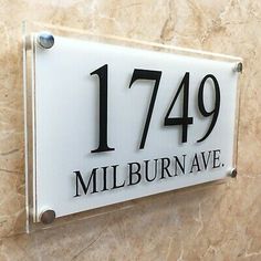 a white and black house number sign mounted to the side of a wall