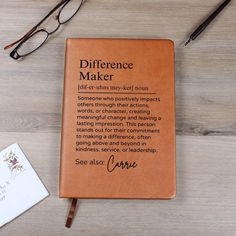 a book with writing on it sitting next to a pen and eyeglasses, along with a notepad