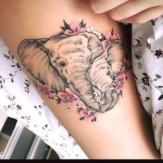 an elephant tattoo on the side of a woman's thigh with flowers around it