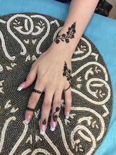 a woman's hand on top of a table covered in black and white designs