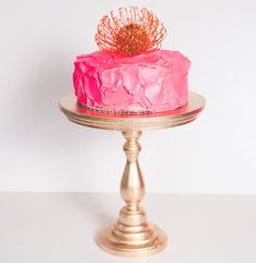 a pink cake sitting on top of a gold plate