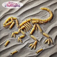 pasta shaped like a lizard on the sand with scissors stuck in it's claws