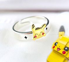 Cute and minimalistic silver open ring, Pokeball cute anime character figure, gold plated, and enamel. These beautiful rings are so cute, perfect for cosplay, collecting, or daily wear! Good quality and intricate design! Sterling silver, gold plated, open ring (adjustable) Default ring inner diameter: 1.8cm Band width: 0.5cm Anime Rings, Bff Rings, Cartoons Band, Pokemon Jewelry, Lightning Bolt Design, Emerald Earrings Drop, Anime Jewelry, Valentines Earrings, Sleeper Earrings