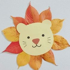 a paper cut out of a cat's face with leaves on the bottom and sides