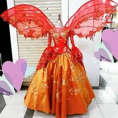 an orange dress with red wings on display in a store front window at valentine's day