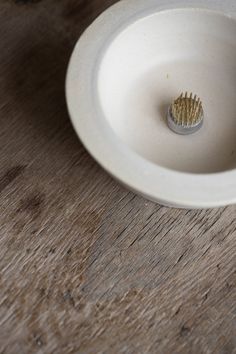 a toothbrush in a white bowl on a wooden table