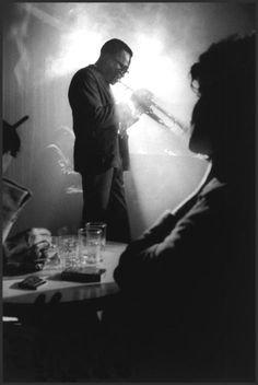 a man standing in front of a table with glasses on it and another person looking at him