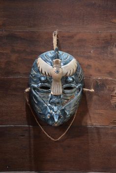 a blue mask hanging on a rope with an eagle painted on the front and back