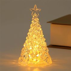 a lighted christmas tree with a star on top and a book in the back ground