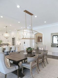 a dining room table with chairs and a chandelier hanging from it's ceiling