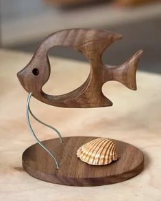 a wooden sculpture with a seashell on it's base and a wire in the middle