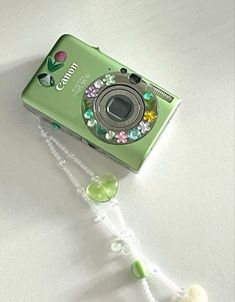 a green camera sitting on top of a white table next to a beaded string