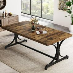 a large wooden table with metal legs in a living room next to a potted plant