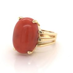 This beautiful Mid-Century cocktail ring features a cabochon cut red coral in 18 karat yellow gold. The coral has a medium scarlet red hue and is set in four golden prongs. The shoulders of the tapered band feature streamlined, openwork spaces for a bit of skin to peek through. From the profile, the Mid-Century details of the ring can truly be admired. The ring has a strong architecture and distinct style, finished in high polish 18k yellow gold. Classic Red Coral Formal Jewelry, Modern Red Cabochon Ring, Elegant Oval Coral Rings, Elegant Coral Oval Rings, Red Oval Cabochon Ring For Formal Occasions, Timeless Red Ring For Formal Occasions, Timeless Red Rings For Formal Occasions, Formal Red Oval Cabochon Ring, Timeless Formal Red Rings