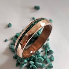 two wedding bands with green stones in the background