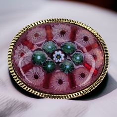 Adorned with an exquisite symphony of colors and intricate patterns, this vintage Italian Millefiori glass brooch is a testament to the enduring legacy of Venetian glassmaking. Crafted by skilled artisans using ancient techniques, the brooch features a mesmerizing array of tiny glass rods fused together, forming a kaleidoscopic patchwork of flowers, stars, and geometric designs. Its smooth, rounded surface shimmers and reflects light, creating a captivating visual display. The brooch is secured with a sturdy pin, allowing it to be elegantly displayed on lapels, jackets, or scarves. The intricate details and vibrant hues of this vintage Millefiori glass brooch evoke a sense of timeless beauty and Italian artistry, making it a cherished collectible and a captivating piece of wearable art. Elegant Multicolor Collectible Brooches, Antique Multicolor Brooch For Gifts, Antique Multicolor Brooches As Gifts, Multicolor Cabochon Brooch For Gift, Multicolor Cabochon Brooch As Gift, Multicolor Cabochon Brooches As Gift, Multicolor Cabochon Brooches For Gifts, Multicolor Cabochon Brooches For Collectors, Victorian Style Multicolor Brooches As Gift