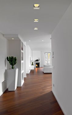 a long hallway with white walls and wooden floors is seen in this image from the side