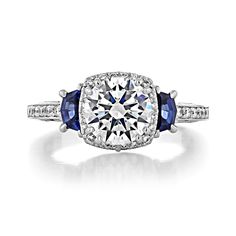 a diamond and sapphire engagement ring with two blue stones on the side, set in white gold