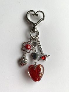 a heart shaped keychain with charms hanging from it's side on a white surface