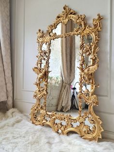 an ornate gold framed mirror sitting on top of a white furnishing next to a window