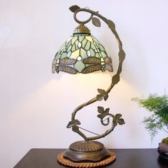 a table lamp sitting on top of a wooden table next to a potted plant