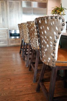 the chairs are lined up on the wooden floor in the kitchen area, with deer hides covering them