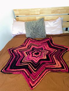 a crocheted blanket laying on top of a bed next to pillows and blankets