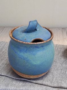 two blue pottery pots sitting on top of a cloth covered place mat next to each other