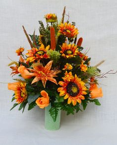 a green vase filled with lots of orange flowers